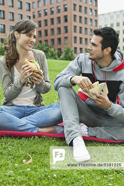 Germany  Berlin  Couple eating food in park