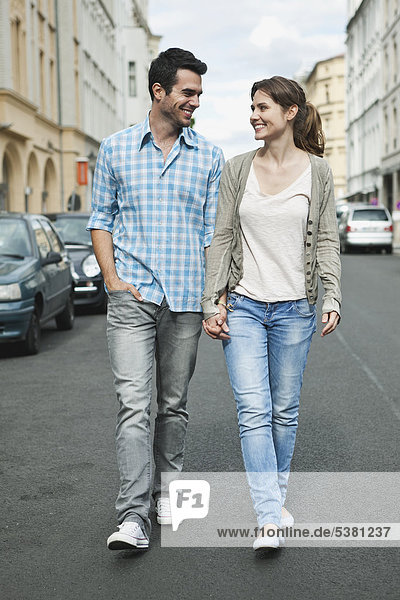 Germany  Berlin  Couple walking hand in hand through city street
