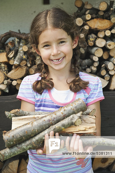 Mädchen mit Brennholz  lächelnd  Portrait