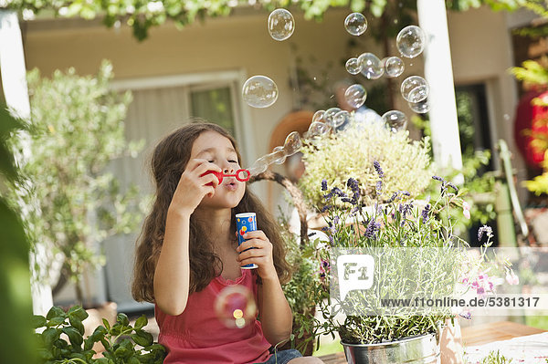 Mädchen bläst Seifenblasen im Garten