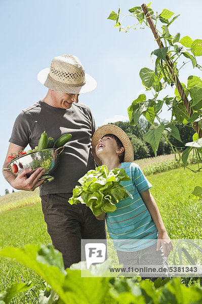 Germany  Bavaria  Grandfather with grandson in vegetable garden  smiling