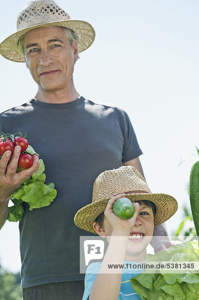 Deutschland  Bayern  Großvater mit Enkel im Gemüsegarten  lächelnd