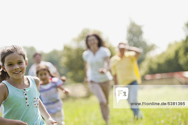 Deutschland  Bayern  Familie beim Picknick gemeinsam im Gras laufen