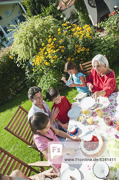 Deutschland  Bayern  Familie bei Kaffee und Kuchen im Garten  lachend