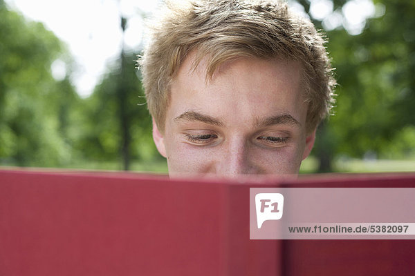Teenager Junge liest im Park