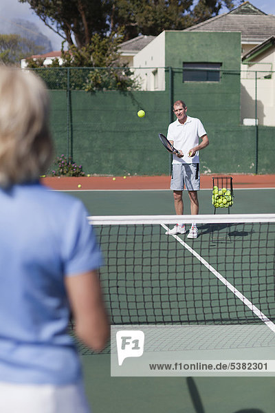 Older couple playing tennis on court