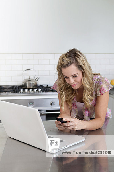 Woman using laptop and cell phone
