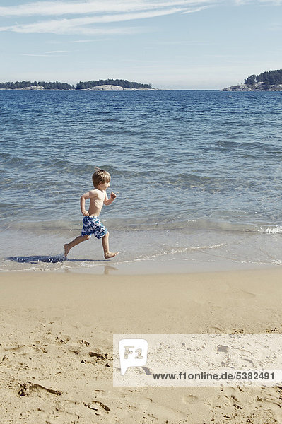 Boy running in waves on beach