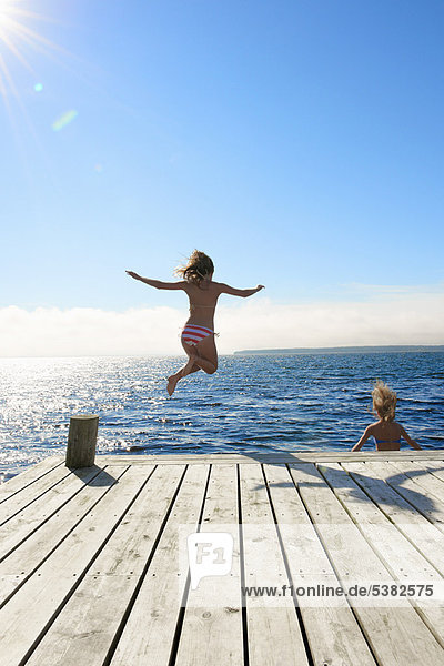 Teenage girls jumping into lake