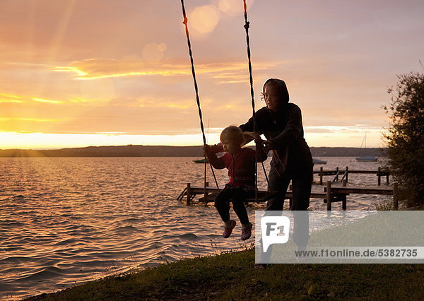 Mother pushing daughter on swing