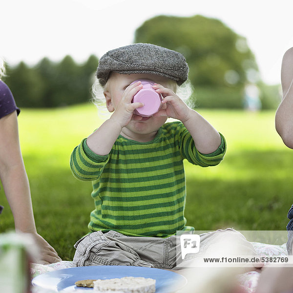Junge trinkt aus Tasse beim Picknick