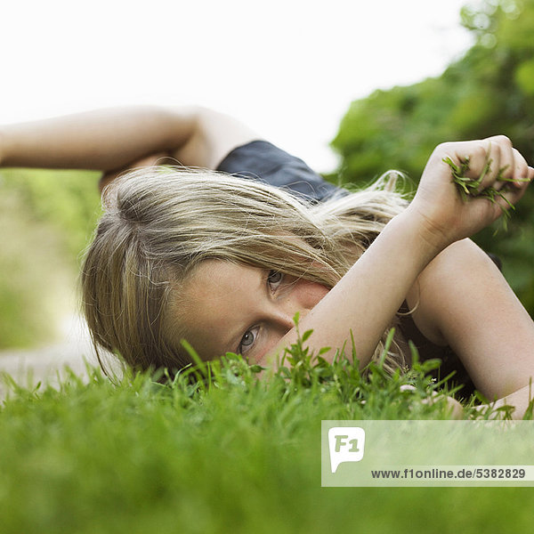 Mädchen liegt auf Gras im Feldweg