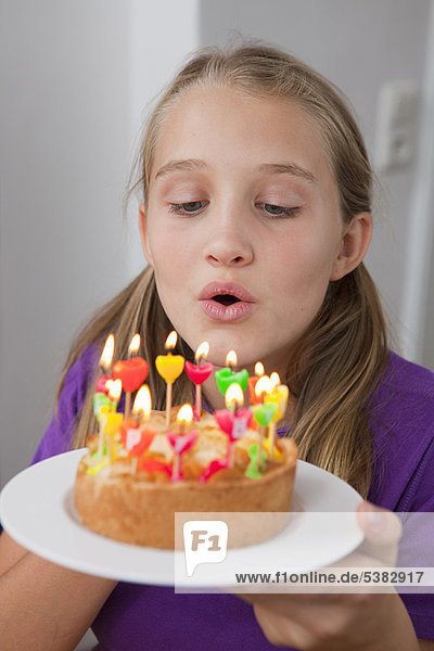 Mädchen beim Ausblasen von Geburtstagskerzen