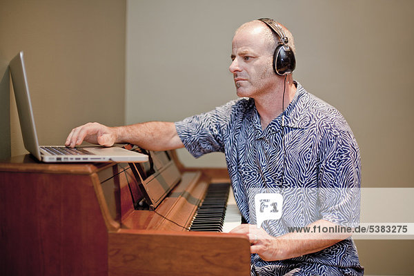 Mann spielt Musik mit Klavier und Laptop