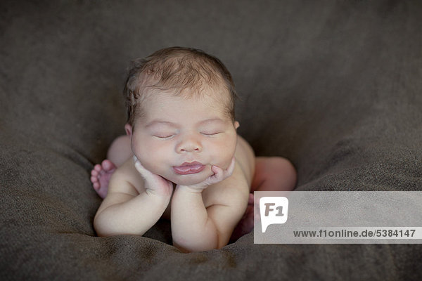 Neugeborenes Baby  5 Tage  schläft mit dem Kopf auf den Händen aufgestützt