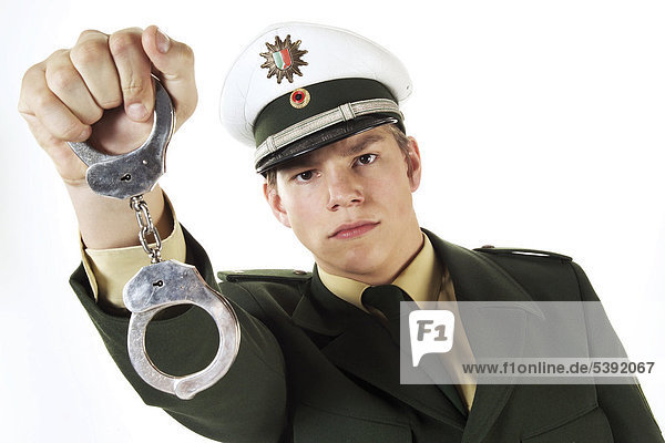 Junger Polizist hält Handschellen