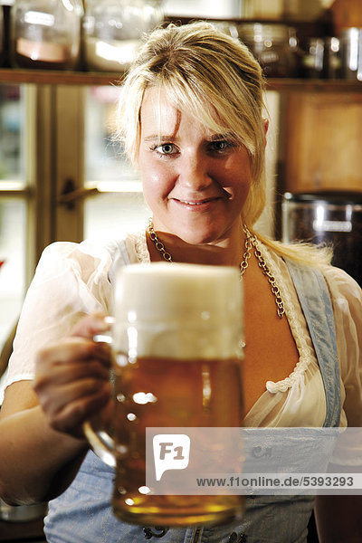 Bayerische Kellnerin im Dirndl hält Bierkrug