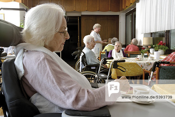 Residents sitting in the dining hall drinking coffee at a nursing home