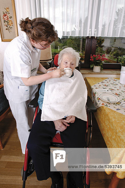 Im Altenheim  Pflegeheim  Pflegerin hilft einer Seniorin beim Trinken