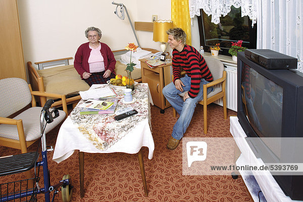Zimmer im Altenheim  Pflegeheim  Seniorin hat Besuch vom Enkel
