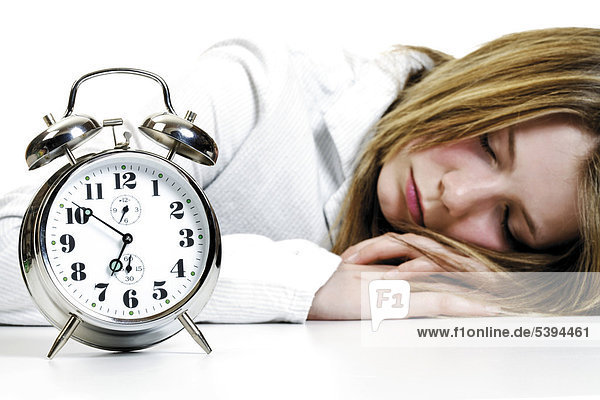 Girl sleeping next to an alarm clock