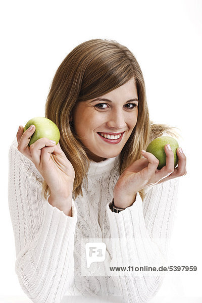Junge Frau im weißen Rollkragenpullover hält grüne Äpfel