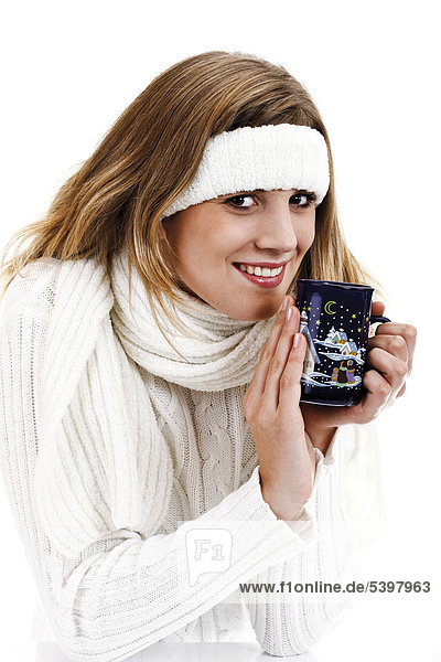 Junge Frau im weißen Rollkragenpullover mit Stirnband und Teetasse