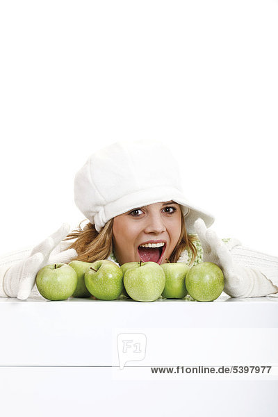 Young woman in a white turtleneck sweater with woolen hat  green apples in front