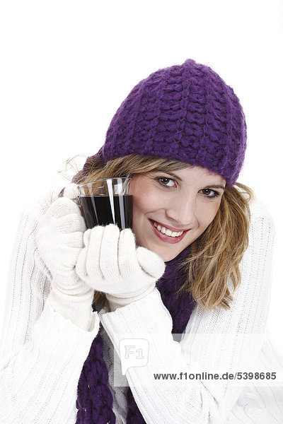Young woman wearing a purple woolen cap and scarf drinking mulled wine  Gluehwein