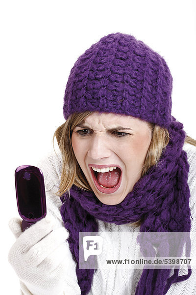 Young woman wearing a purple woolen cap and scarf screaming into a mobile telephone