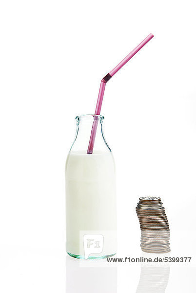 Milch in Flasche mit Trinkhalm und Münzstapel