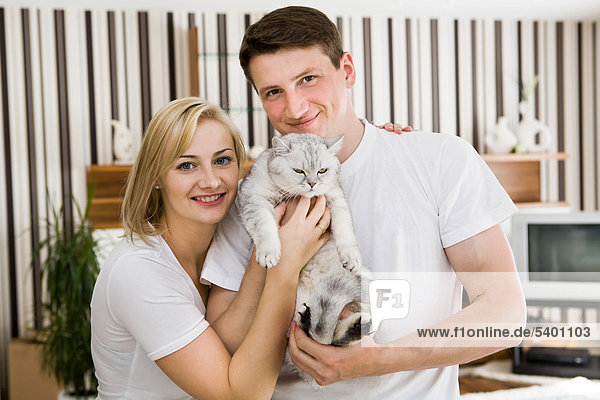 Glückliches  junges Paar mit Katze in ihrer Wohnung