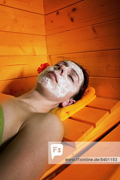 Young woman with facial mask in the sauna