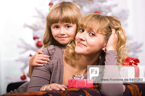 Junge Frau und Mädchen mit Weihnachtsgeschenk vor Weihnachtsbaum