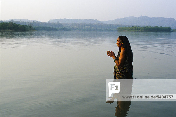 Eine Frau steht im kalten klaren Wasser des Flusses Ganges und betet zu Gott Haridwar Uttarakhand früher Uttaranchal Indien Asien