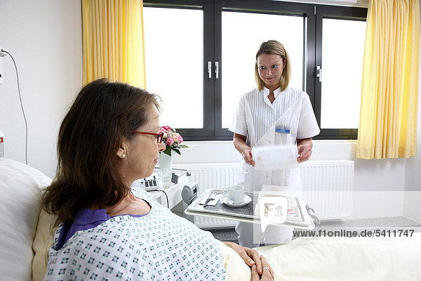 Patientin im Krankenbett  Krankenschwester bringt eine Mahlzeit auf einem Tablett  Krankenhaus