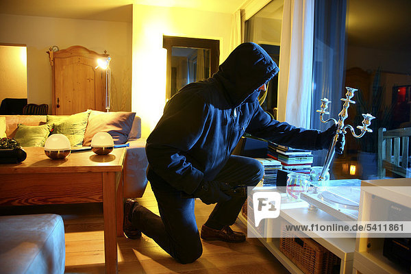 Burglar enters apartment  searches the rooms for valuables  symbolic image for domestic burglary