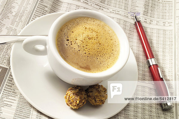 Eine Tasse Kaffee auf Börsenzeitung - Symbol für Kaffeepause im Büro