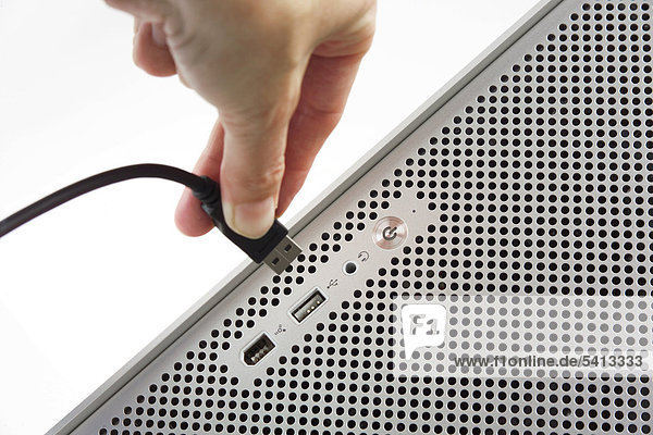 Hand plugging a USB cord into a computer