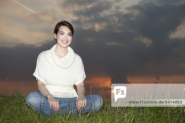 Lächelnde junge Frau auf einer Wiese  Sonnenuntergang