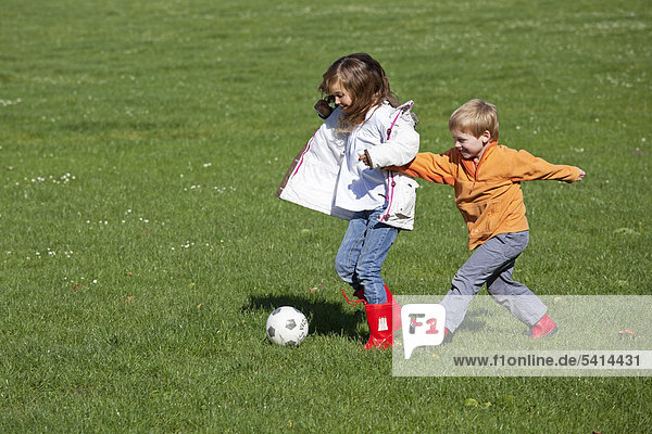 Mädchen und Junge spielen Fußball