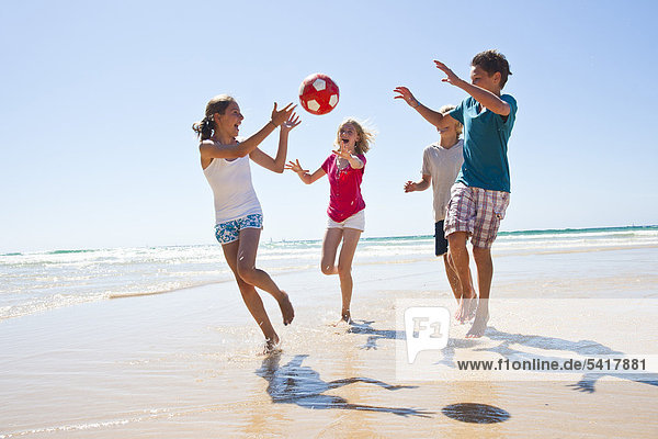 Teenager spielen Ball am Strand