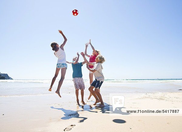 Teenager spielen Ball am Strand