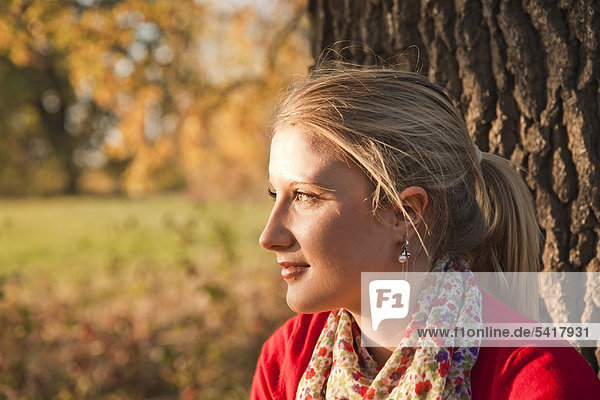 Young woman leaning against tree