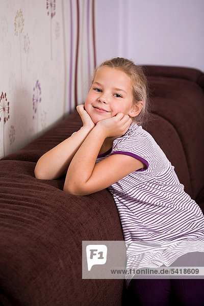 8-jähriges Mädchen sitzt auf Sofa