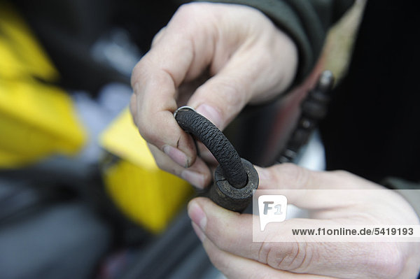 Hands holding a porous  brittle brake pipe of a vehicle