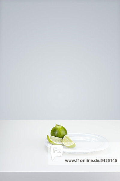 Limetten (Citrus latifolia) auf einem weißen Teller