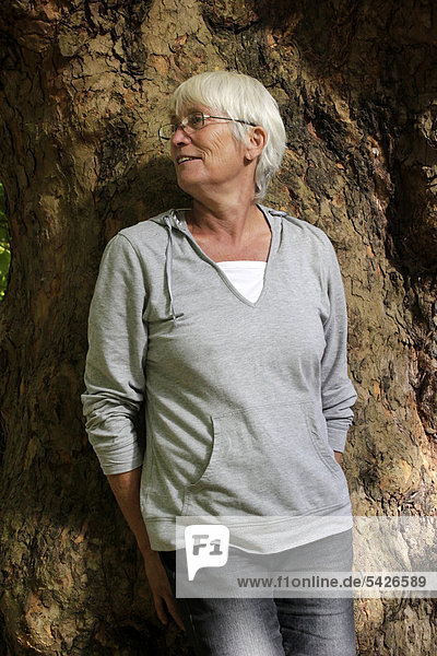 Elderly woman  senior citizen  leaning against a tree