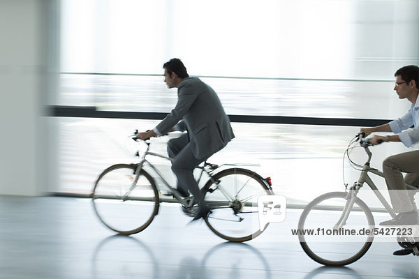 Businessmen riding bicycles indoors  silhouette  blurred motion