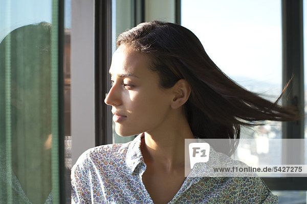 Woman looking out of window  sunshine on face